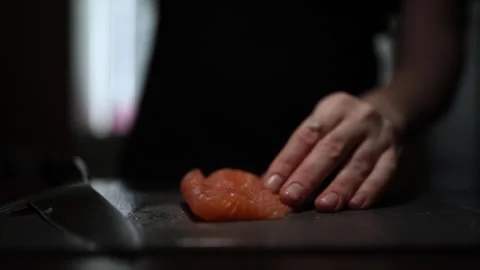 Close-Up of Hands Slicing Fresh Salmon Fillet on a Dark Background Видео 296234420