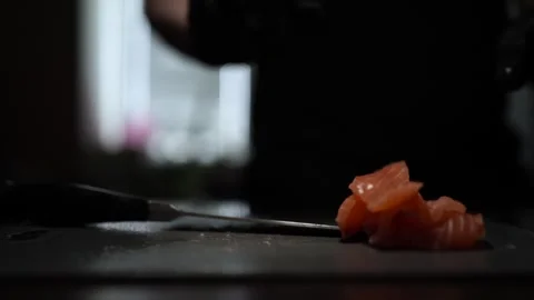 Close-Up of Hands Slicing Fresh Salmon Fillet on a Dark Background Stock Footage 296234432