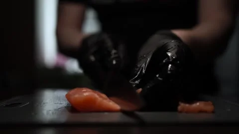 Close-Up of Hands Slicing Fresh Salmon Fillet on a Dark Background Stock Footage 296234439