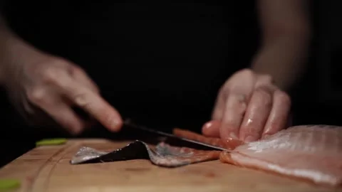 Close-Up of Hands Slicing Fresh Salmon Fillet on a Dark Background Stock Footage 296234642