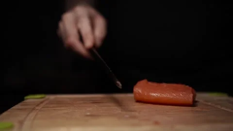 Close-Up of Hands Slicing Fresh Salmon Fillet on a Dark Background Vídeo Stock 296234699