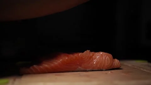 Close-Up of Hands Slicing Fresh Salmon Fillet on a Dark Background Stock Footage 296234760
