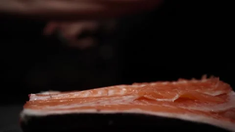 Close-Up of Hands Slicing Fresh Salmon Fillet on a Dark Background Vídeos de archivo 296234859