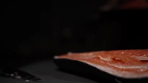 Close-Up of Hands Slicing Fresh Salmon Fillet on a Dark Background 스톡 동영상 296234905
