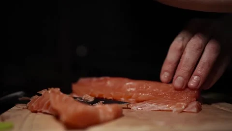 Close-Up of Hands Slicing Fresh Salmon Fillet on a Dark Background Stockbeeldmateriaal 296422016