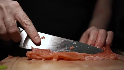 Close-Up of Hands Slicing Fresh Salmon Fillet on a Dark Background Stock Footage 296422017