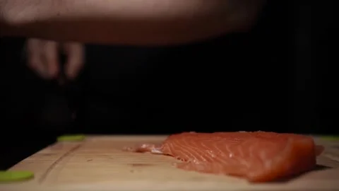 Close-Up of Hands Slicing Fresh Salmon Fillet on a Dark Background Video stock 296422117