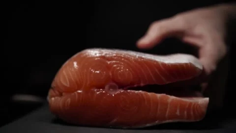 Close-Up of Hands Slicing Fresh Salmon Fillet on a Dark Background 스톡 동영상 296422944