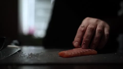 Close-Up of Hands Slicing Fresh Salmon Fillet on a Dark Background Stock Footage 296423418