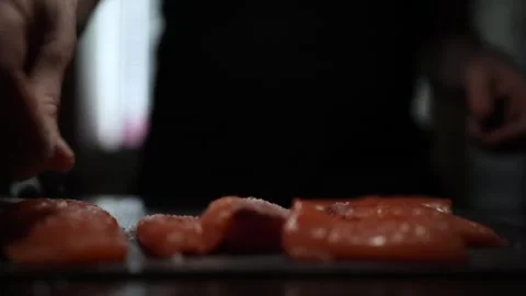 Close-Up of Hands Slicing Fresh Salmon Fillet on a Dark Background Видео 296423425