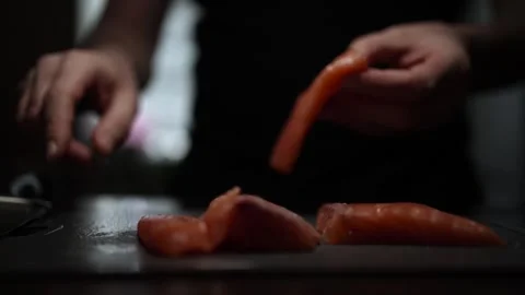 Close-Up of Hands Slicing Fresh Salmon Fillet on a Dark Background Stock Footage 296423502