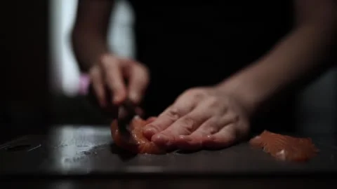 Close-Up of Hands Slicing Fresh Salmon Fillet on a Dark Background 스톡 동영상 296423984