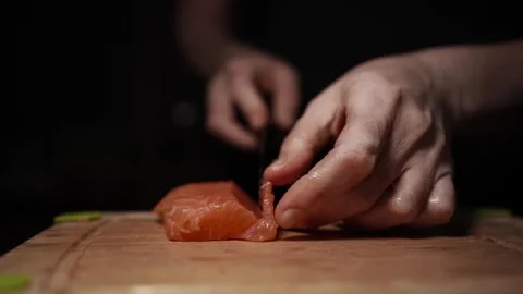 Close-Up of Hands Slicing Fresh Salmon Fillet on a Dark Background Stock-Footage 296424864