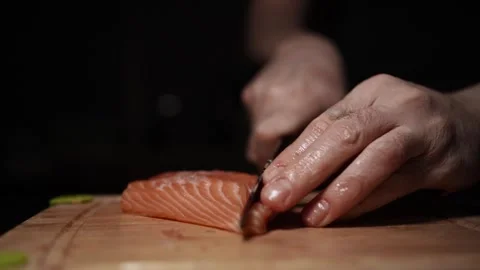 Close-Up of Hands Slicing Fresh Salmon Fillet on a Dark Background Stock-Footage 296425182