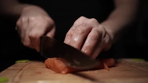Close-Up of Hands Slicing Fresh Salmon Fillet on a Dark Background Stock-Footage 296425359