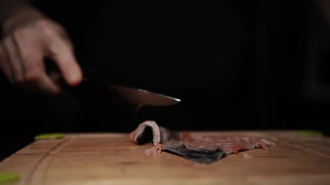 Close-Up of Hands Slicing Fresh Salmon Fillet on a Dark Background Stock Footage 296426713