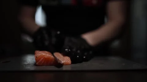 Close-Up of Hands Slicing Fresh Salmon Fillet on a Dark Background Vídeos de archivo 296426715