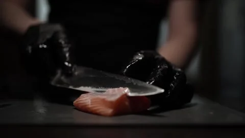 Close-Up of Hands Slicing Fresh Salmon Fillet on a Dark Background 스톡 동영상 296426877