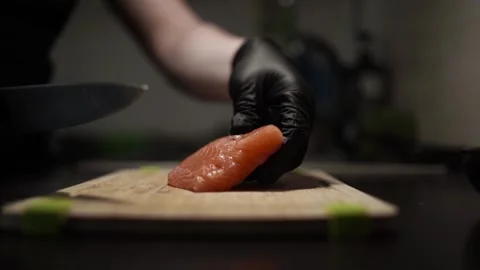 Close-Up of Hands Slicing Fresh Salmon Fillet on a Dark Background Stock Footage 296427709