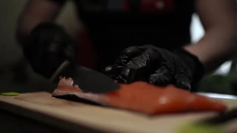 Close-Up of Hands Slicing Fresh Salmon Fillet on a Dark Background Video stock 296428167