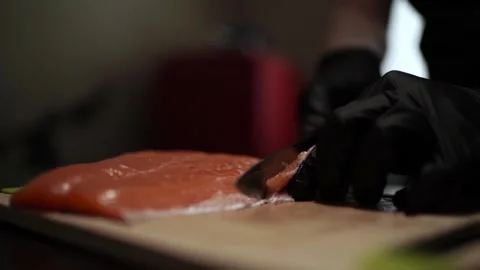 Close-Up of Hands Slicing Fresh Salmon Fillet on a Dark Background Видео 296428269