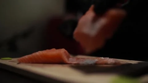 Close-Up of Hands Slicing Fresh Salmon Fillet on a Dark Background Stock-Footage 296428480