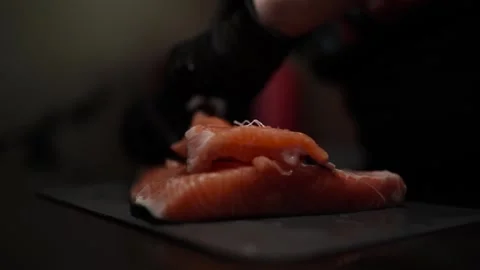 Close-Up of Hands Slicing Fresh Salmon Fillet on a Dark Background 스톡 동영상 296428513