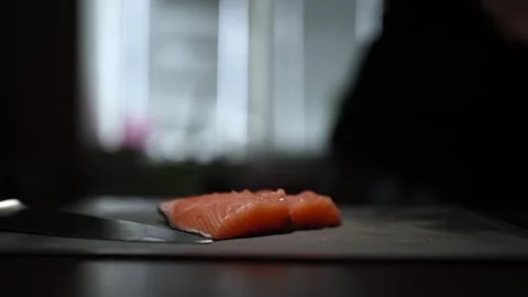 Close-Up of Hands Slicing Fresh Salmon Fillet on a Dark Background Stock Footage 296428535