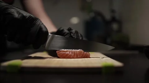 Close-Up of Hands Slicing Fresh Salmon Fillet on a Dark Background 스톡 동영상 303891284
