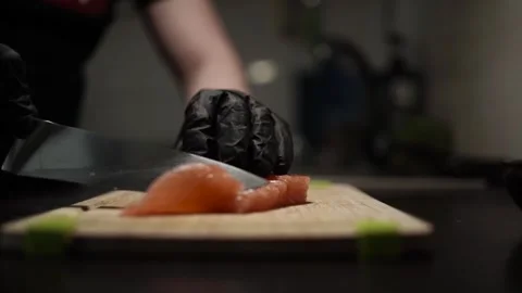 Close-Up of Hands Slicing Fresh Salmon Fillet on a Dark Background Stock Footage 303891285