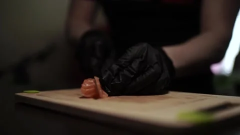 Close-Up of Hands Slicing Fresh Salmon Fillet on a Dark Background Видео 303891409