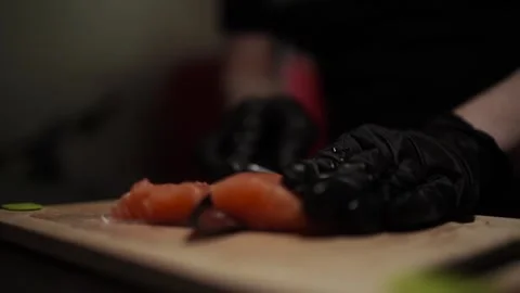 Close-Up of Hands Slicing Fresh Salmon Fillet on a Dark Background Stock Footage 303891850