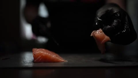 Close-Up of Hands Slicing Fresh Salmon Fillet on a Dark Background Video stock 303891853