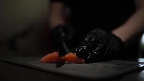 Close-Up of Hands Slicing Fresh Salmon Fillet on a Dark Background Stock Footage 303891928