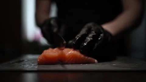 Close-Up of Hands Slicing Fresh Salmon Fillet on a Dark Background Stockbeeldmateriaal 303892013