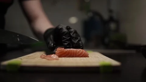 Close-Up of Hands Slicing Fresh Salmon Fillet on a Dark Background Stock Footage 303893771