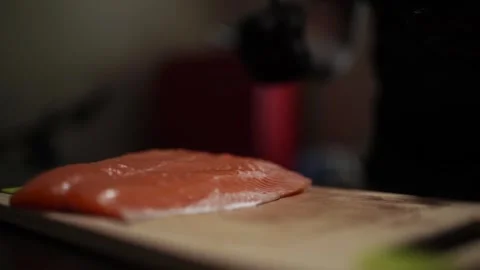 Close-Up of Hands Slicing Fresh Salmon Fillet on a Dark Background Stock-Footage 303893797