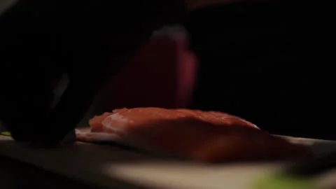 Close-Up of Hands Slicing Fresh Salmon Fillet on a Dark Background Video stock 303893799