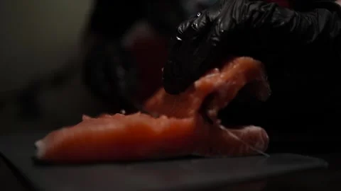 Close-Up of Hands Slicing Fresh Salmon Fillet on a Dark Background 스톡 동영상 303893846