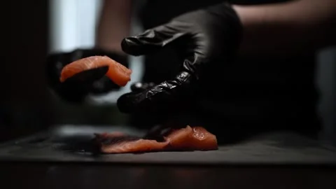 Close-Up of Hands Slicing Fresh Salmon Fillet on a Dark Background 스톡 동영상 303893859