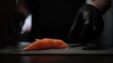 Close-Up of Hands Slicing Fresh Salmon Fillet on a Dark Background 스톡 동영상 303893871