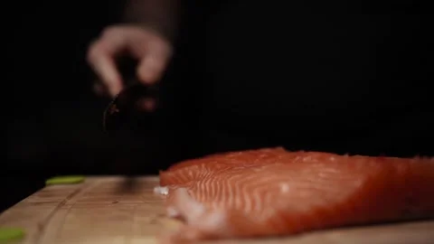 Close-Up of Hands Slicing Fresh Salmon Fillet on a Dark Background 스톡 동영상 303895367