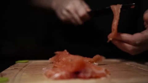 Close-Up of Hands Slicing Fresh Salmon Fillet on a Dark Background Video stock 303895385