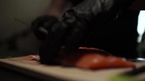 Close-Up of Hands Slicing Fresh Salmon Fillet on a Dark Background Stock-Footage 303895401