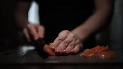 Close-Up of Hands Slicing Fresh Salmon Fillet on a Dark Background Video stock 303896677