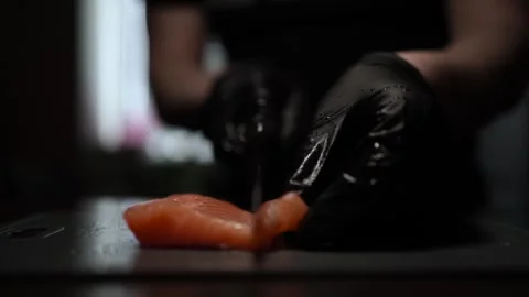 Close-Up of Hands Slicing Fresh Salmon Fillet on a Dark Background Vídeos de archivo 303896957