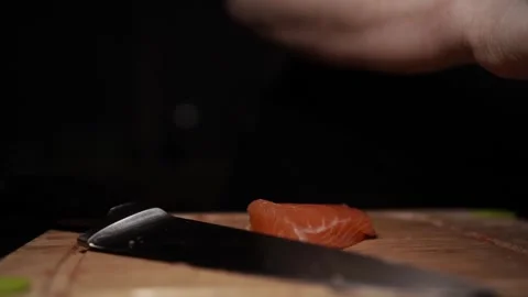 Close-Up of Hands Slicing Fresh Salmon Fillet on a Dark Background 스톡 동영상 303897067