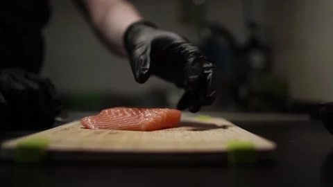 Close-Up of Hands Slicing Fresh Salmon Fillet on a Dark Background Stock-Footage 303897097