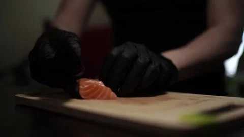 Close-Up of Hands Slicing Fresh Salmon Fillet on a Dark Background Stock Footage 303897110