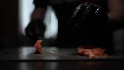 Close-Up of Hands Slicing Fresh Salmon Fillet on a Dark Background Stock Footage 303898690